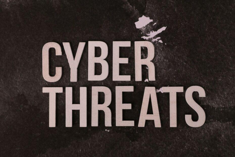 The phrase 'Cyber Threats' displayed on a textured dark background, emphasizing digital security.